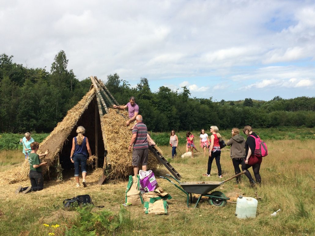 Visitor and friends looking and helping with artwork wattle and daub construction
