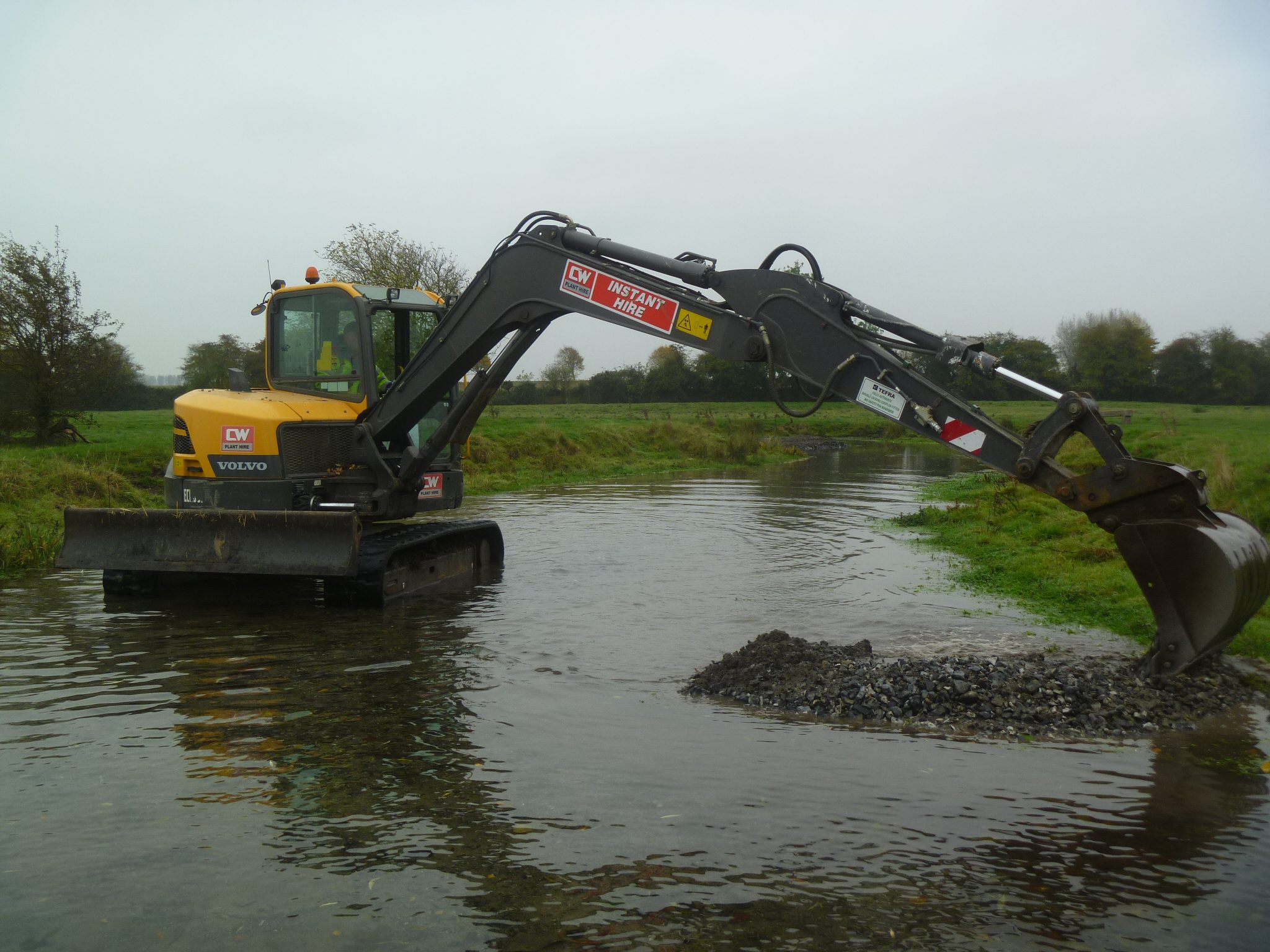 Digger working in river to create berm and pool