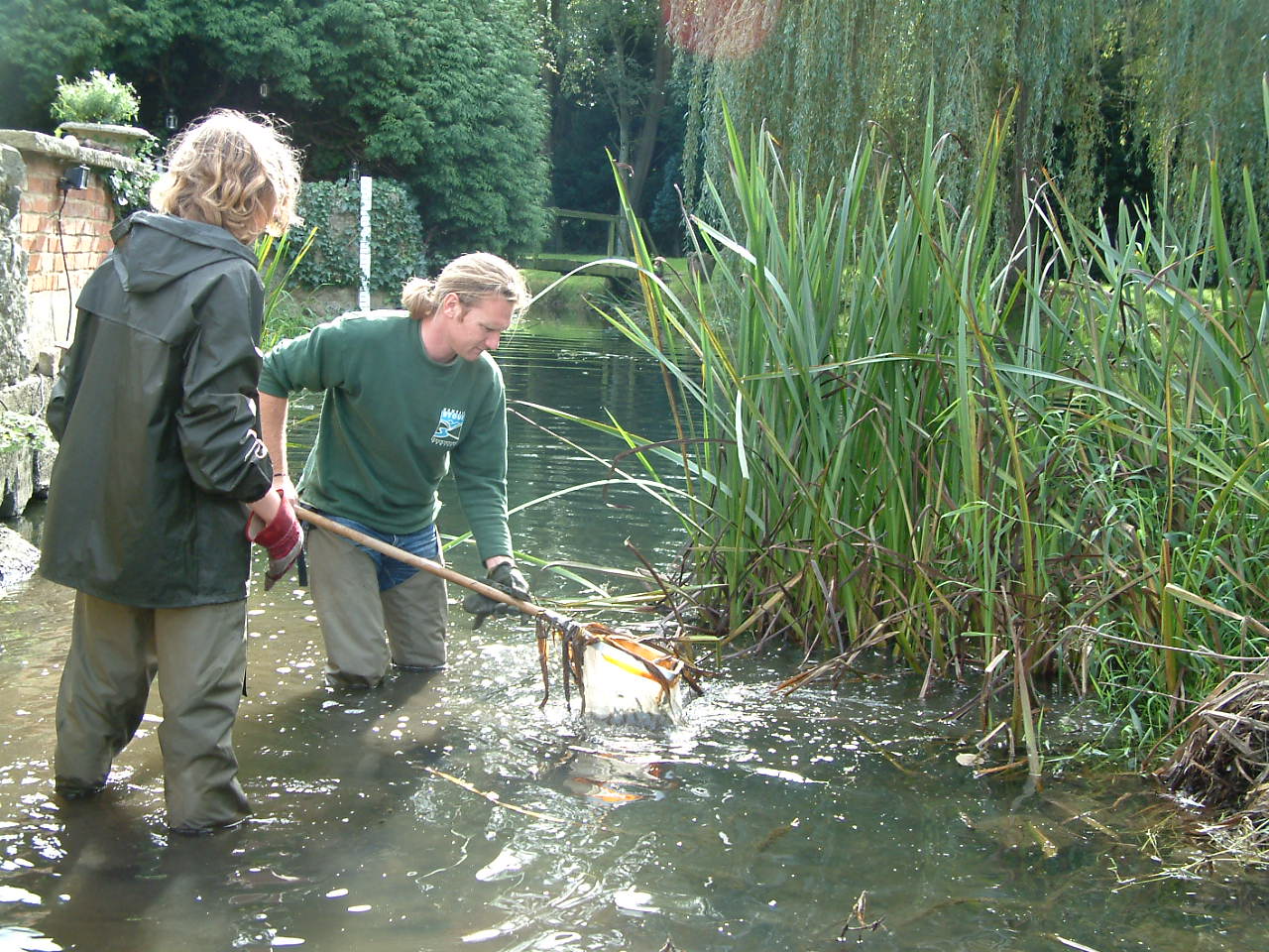 2 kscp staff wearing waders in river using nets for surveying