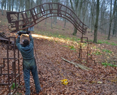 man using angle grinder to cut metal sculpture in Kings Wood