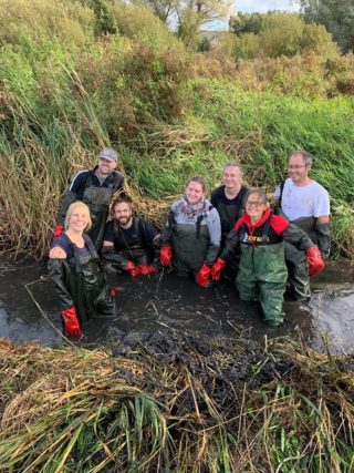 volunteers in muddy water ditch